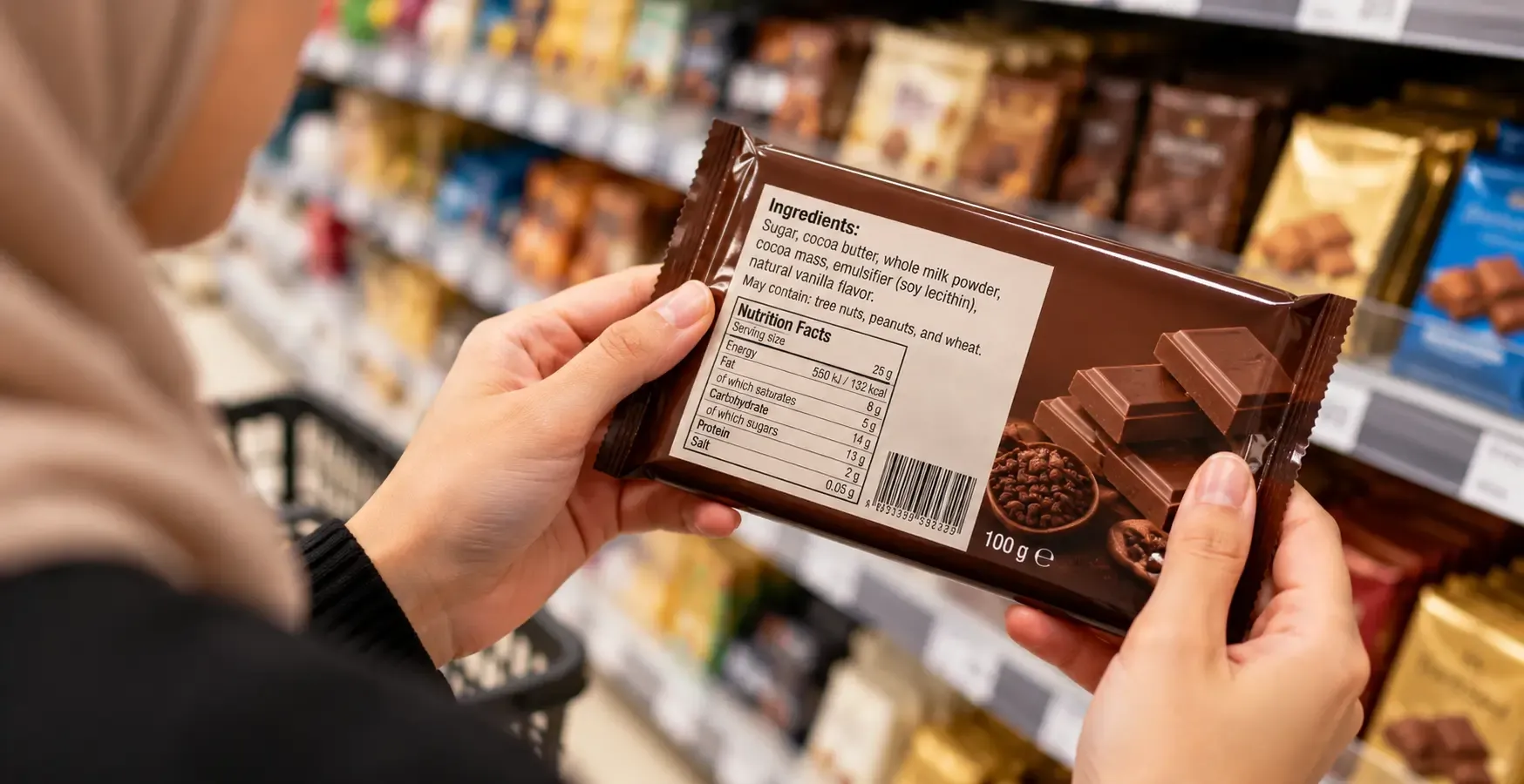 Person holding a premium chocolate bar checking the ingredients list in a supermarket aisle