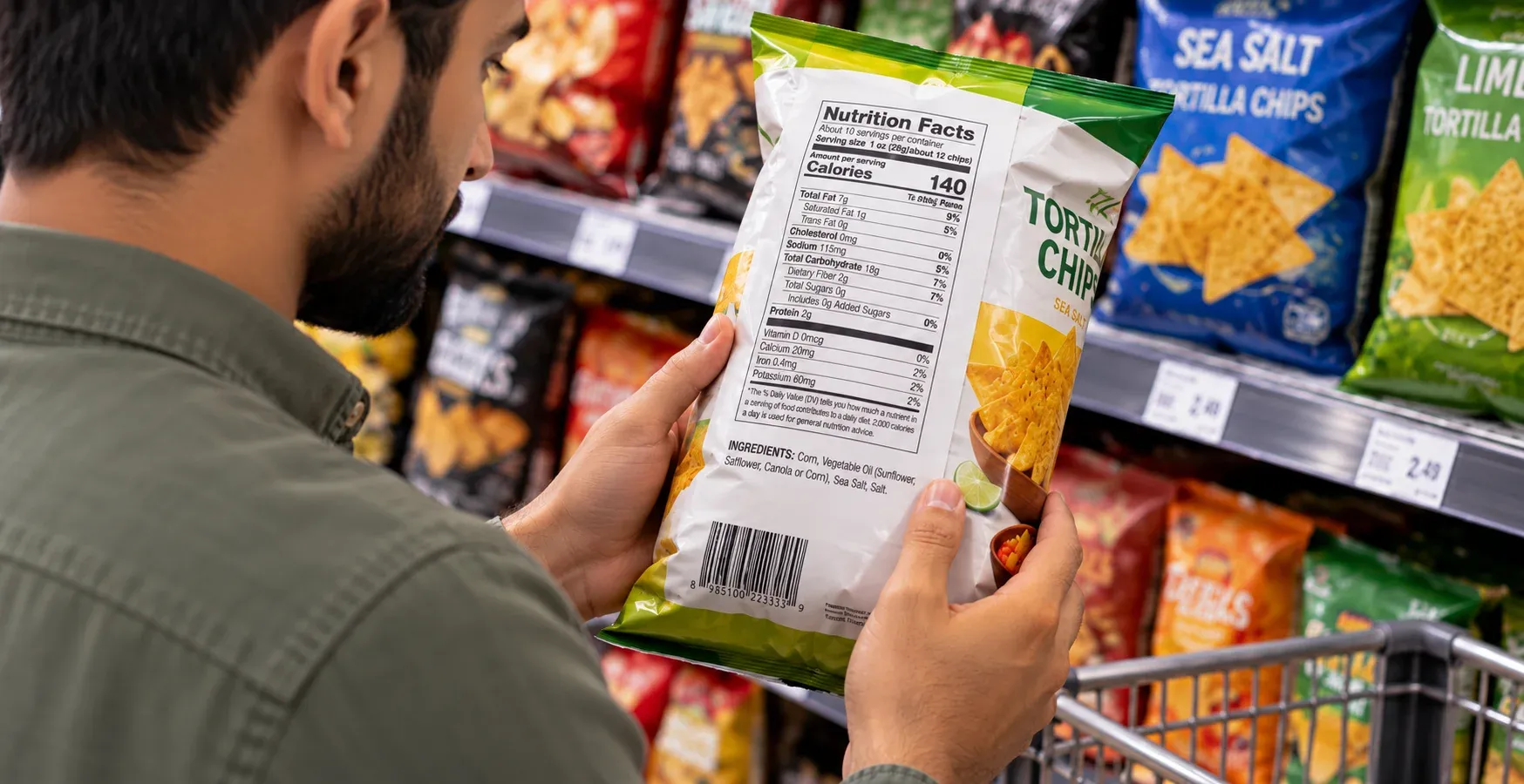 Person holding a bag of tortilla chips while checking the ingredient list in a grocery store